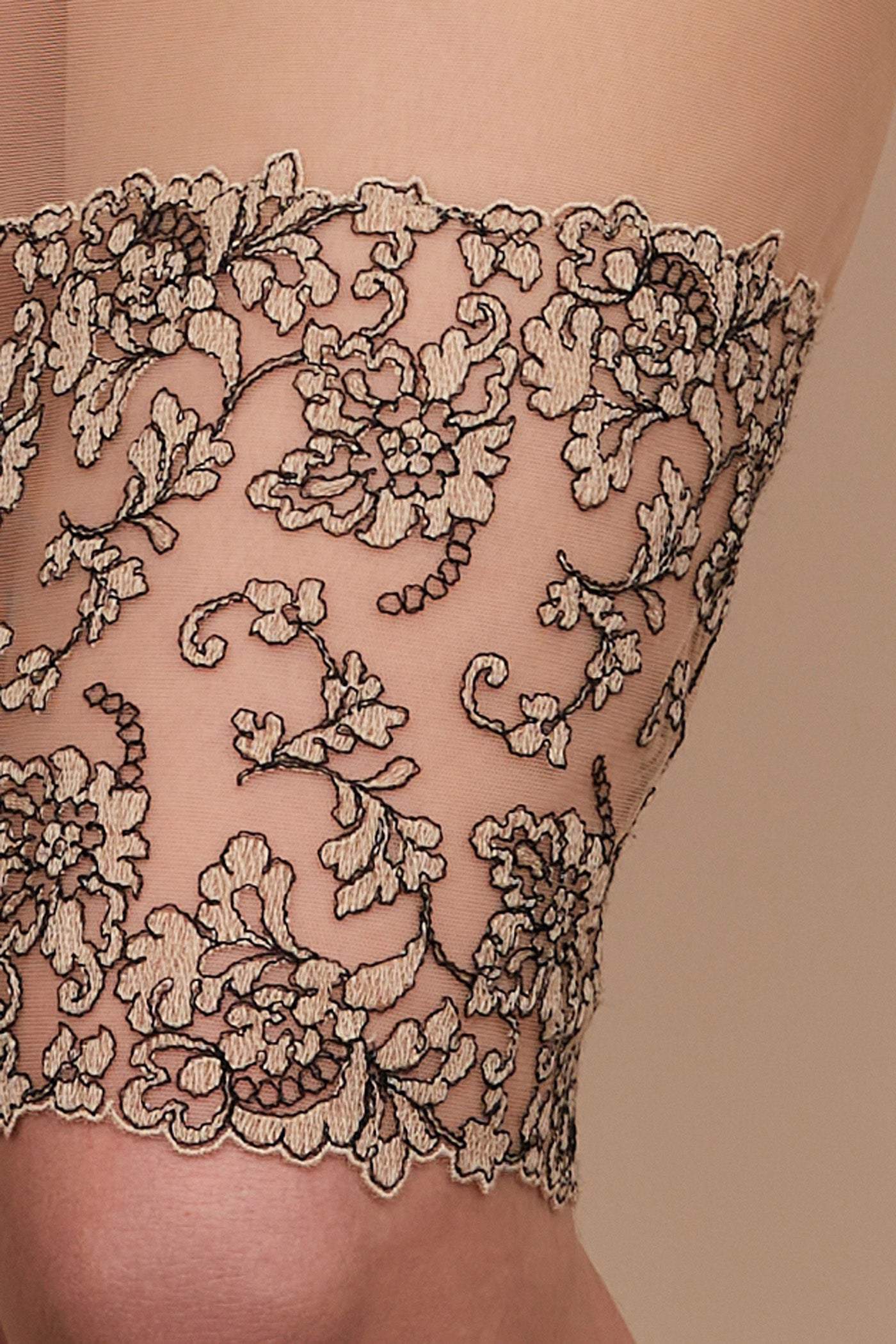 Detail of black and cream embroidery on tulle on bottom of sheer slip